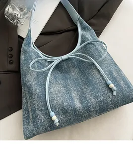 Dettaglio della borsa tote blu con decorazione a fiocco e coulisse con perline decorative