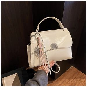 Detail of white glossy PU tote bag featuring silver hardware and woven tassel charm