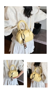 Detail view of a yellow mini bowling bag with a cute monkey charm and pearl strap