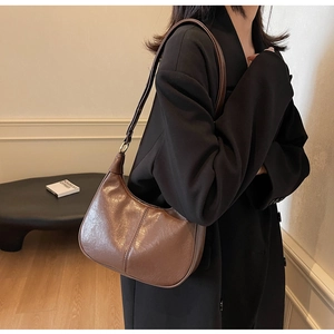 Close-up of brown vintage PU leather hobo bag with gold metal rings and fine stitching