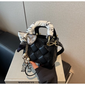 Detail of black quilted mini handbag featuring silk scarf handle and pearl leaf charm