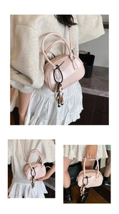 Detail view of pink glossy leather bowling bag with doll pendant and adjustable strap