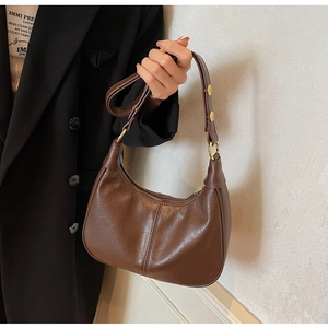 Close-up of soft brown leather dumpling bag showing metal buckle and rivet hardware
