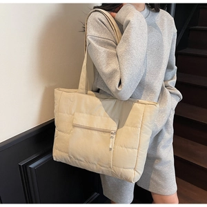 Détail d'un sac cabas beige matelassé avec une poche avant zippée pratique et une texture douce