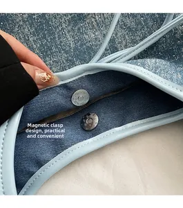 Dettaglio della chiusura magnetica e del bordo in pelle su una borsa shopping in denim