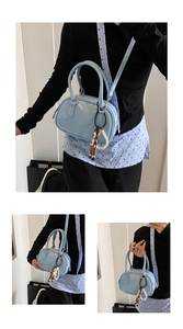 Detail view of light blue patent leather bowling bag with doll and pearl pendant charms
