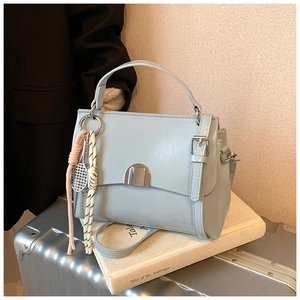 Detail of light blue faux leather tote with silver buckle and mini tennis racket charm