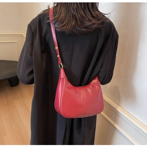 Detailed back view of a red crescent shoulder bag with glossy faux leather and golden buckle