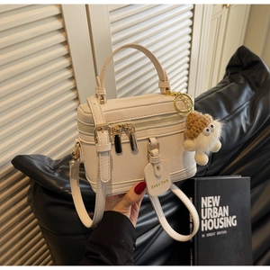 Detail of off-white lychee grain leather box bag featuring a plush monster charm