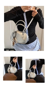 Detail of silver bowling bag with metallic finish, pearl chain, and cute doll charm