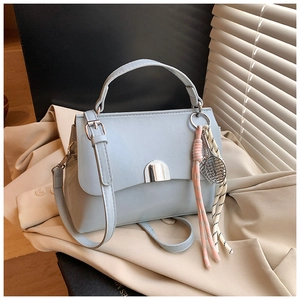 Detail of light blue faux leather tote bag with metal buckle and tennis racket charm