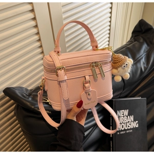Detailed close-up of pink litchi grain leather box bag with a cute white teddy bear charm