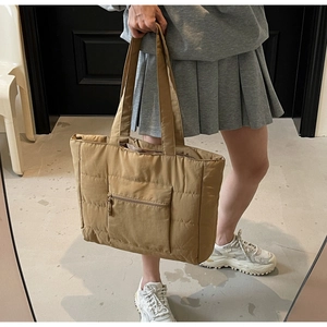 Détail du grand sac cabas matelassé kaki avec poche zippée porté sur une tenue décontractée