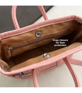 Vista interior del bolso de cuero rosa con cierre de presión y bolsillo con cremallera