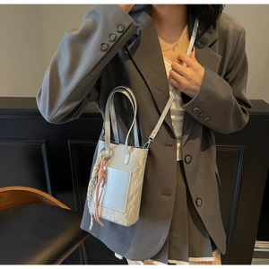 Detail of light blue-grey textured crossbody bag with brand logo and colorful knot charm