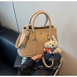 Vue détaillée du cuir grainé camel avec texture litchi et accessoire de sac ours en peluche