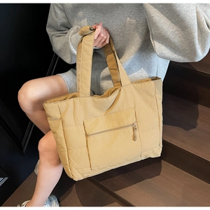 Détail d'un sac cabas matelassé kaki avec une poche zippée pratique à l'avant pour objets