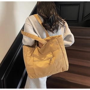 Vue de dos d'un mannequin portant un grand sac cabas matelassé jaune gingembre