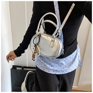 Silver metallic bowling bag shown worn crossbody with a decorative doll and pearl chain