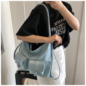 Detail of light blue hobo bag with decorative pockets shown on shoulder of a model
