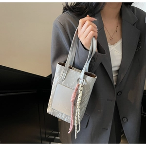 Detail of grey marble textured handbag with stylish pink bow charm and elegant leather finish