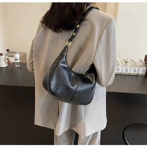 Detail of black glossy wrinkled leather hobo bag with vintage golden hardware