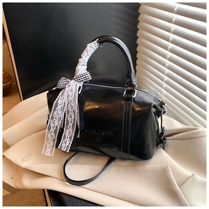Detail of black Boston bag with lace ribbon, checkered bow and embossed logo