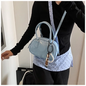 Detail of light blue patent leather Boston bag with pearl charm and cute mascot on a model