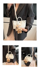 Primer plano mini bolso blanco textura litchi con colgante de oso de peluche en una modelo