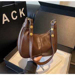Detail of dark brown semi-moon shoulder bag featuring golden rivets and smooth leather texture
