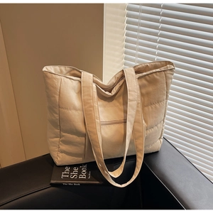 Gros plan du sac cabas matelassé beige avec tissu imperméable et poche zippée latérale