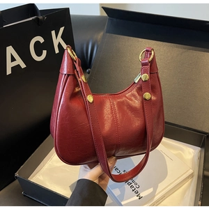 Detail view of burgundy hobo bag with oil wax leather texture and gold rivets in a gift box