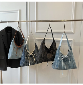 Serie di borse hobo in denim con grandi fiocchi decorativi appese a un espositore
