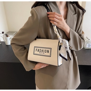 Detail of cream shoulder bag with black contrast edges and silk scarf wrapped chain strap
