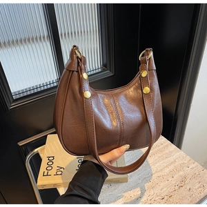 Detailed macro view of dark brown leather hobo bag with vintage texture and gold hardware