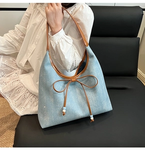 Dettaglio della borsa hobo in denim azzurro con un grande fiocco e finiture in cuoio