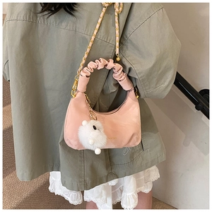Detail of light pink crescent bag featuring pleated cloud handle and cute plush rabbit charm