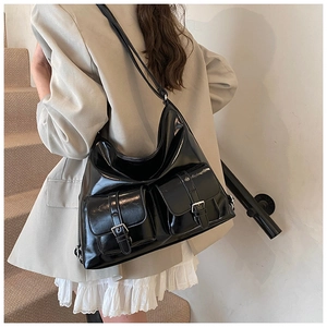 Detail view of a black glossy hobo bag with two front pockets and silver buckles
