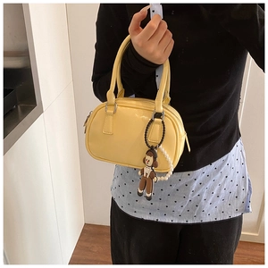 Chic bright yellow patent leather boston bag with a cute cartoon character charm