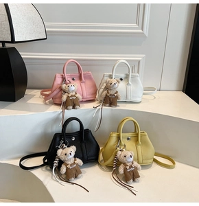 Detalle de cuatro mini bolsos de colores rosa, blanco, negro y amarillo con dijes de oso
