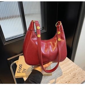 Detail of red glossy pleated leather handbag with golden round buckle and rivet accents