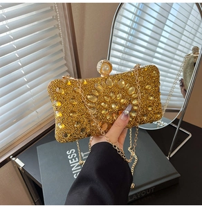 Detail of luxury gold evening bag featuring sparkling crystals and large pearl clasp
