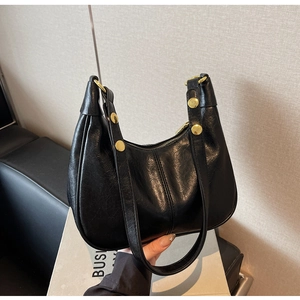 Detailed close-up of a black half-moon bag featuring large gold metal rivets on the strap
