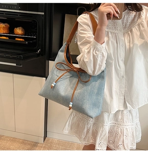 Dettaglio della borsa tote in denim blu con motivo stellato e manici in pelle marrone