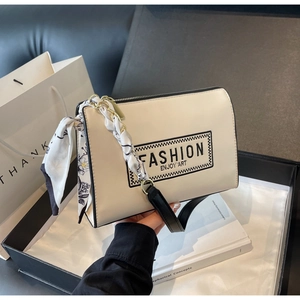 Detail view of cream leather shoulder bag with silk scarf chain and logo in gift box