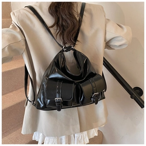 Detail of glossy black faux leather backpack featuring silver buckles and adjustable straps