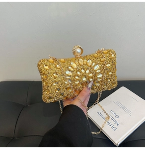 Detail of luxury gold evening clutch with rhinestones, yellow crystals and pearl clasp