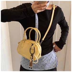 Close-up of bright yellow patent leather bowling bag with cute monkey charm accessory