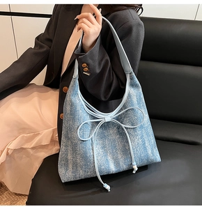 Dettaglio di borsa tote in denim azzurro con un grande fiocco decorativo applicato