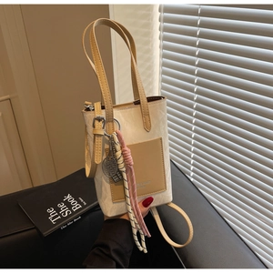 Detail view of contrast stitching small tote with mini tennis racket charm and texture